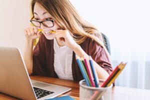 Lady biting on a pencil while working on the computer in order to introduce the section, "Leveraging Digital Tools While Maintaining Personal Connection."